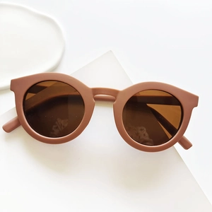 Close-up of retro round kids sunglasses with matte brown frames on white decor