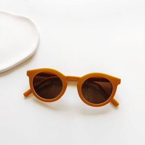 Detail of yellow round children's sunglasses with dark lenses on a white background