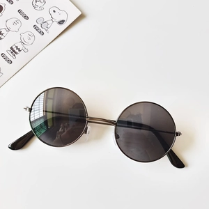 Macro view of retro round children's sunglasses with slim metal frames and dark lenses
