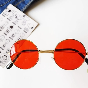 Detail view of round vintage kids sunglasses with red lenses and gold metal frames