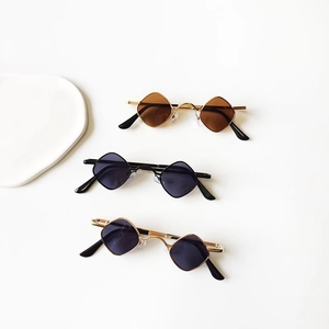 Stylish kids' rhombus-shaped sunglasses in gold and black frames on a minimal background
