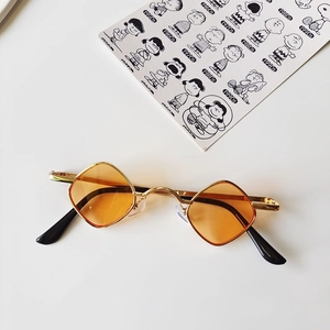 Detail view of gold metal diamond frame sunglasses with orange lenses for children