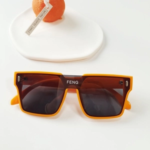 Détail de lunettes de soleil carrées orange pour enfants avec verres foncés et rivets