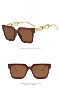 Detail of square oversized sunglasses in burgundy with gold chunky chain temples