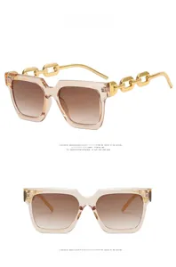 Detail view of champagne square sunglasses featuring gold chain metal temples and brown lenses