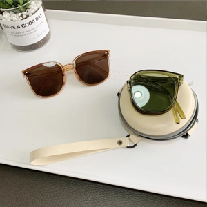 Foldable sunglasses with round EVA zipper storage case in a stylish minimalist setting