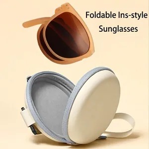 Portable amber folding sunglasses and off-white round EVA storage case with wrist strap