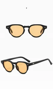 Macro detail of glossy black frame sunglasses with transparent orange lenses and silver rivets