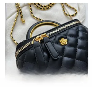 Detail of black quilted leather mini box bag with golden metal handle and flower charm