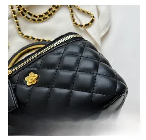 Detail of black quilted leather stitching with golden camellia floral charm and chain