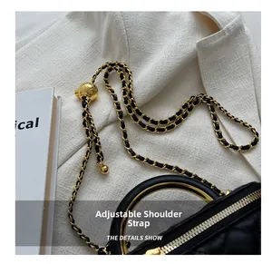 Close-up of black quilted leather box bag with gold metal handle and adjustable chain strap