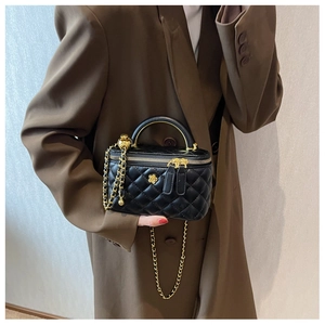 Close-up of quilted black leather vanity bag with gold floral charms and chain strap