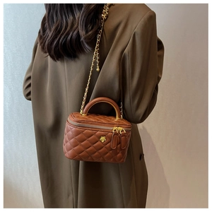 Detailed view of brown quilted vanity case bag with golden flower clasp and chain strap
