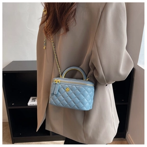 Detail of light blue quilted chain bag featuring golden flower logo and dual zippers