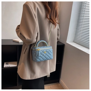 Detail view of light blue quilted chain vanity bag worn by model on shoulder