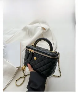 Detail of a black quilted leather mini box bag with golden flower charm and chain strap
