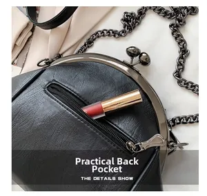 Detail of minimalist black crossbody bag showing back zipper pocket and metal chain strap