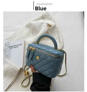 Detail of blue quilted mini box bag with gold chain strap and floral buckle accent