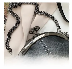 Detail of lychee pattern leather bag with metallic clasp, chain strap and white stitching