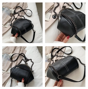 Detail view of black shell bag with white contrast stitching and vintage metal clasp