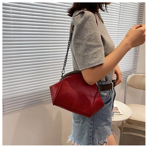 Close-up of dark red quilted shell bag featuring retro metal frame and chain strap detail