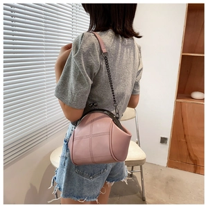 Pink shell-shaped crossbody bag with decorative cross-stitching and metal chain strap