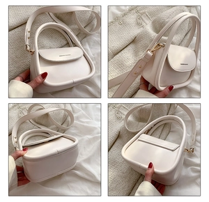 Detail view showing minimalist ivory square bag with circular handle and metal hardware