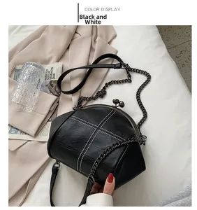 Detail of vintage black shell bag with white stitching and metal chain strap