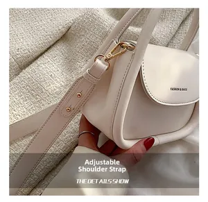 Detail view of the adjustable shoulder strap and hardware on the creamy leather crossbody bag
