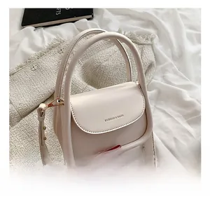 Macro shot of cream leather handbag detailing golden metal buckles and handle texture