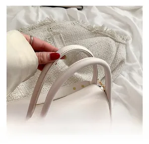 Detail of cream white leather handbag with golden hardware and fashion logo text