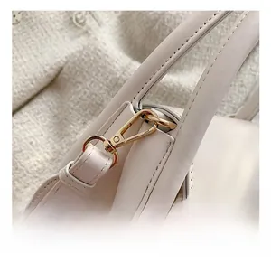 Macro detail of high-quality gold metal hook and leather stitching on beige square bag