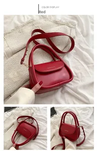 Detail view of red faux leather handbag with gold hardware and logo on cream fabric