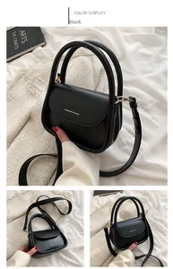 Detail view of black leather mini square bag with golden ring handles and fashion logo