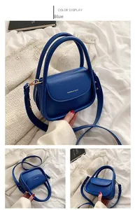 Detail view of the royal blue crossbody bag featuring a golden brand logo and wide strap