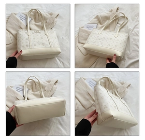 Detail of white tote bag with bear print pattern and metal logo plate on the front
