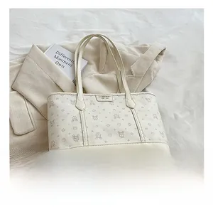 Detail of a beige tote bag with cute rabbit prints and brand leather label