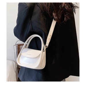 Detailed view of a white leather crossbody bag with fashion text and golden metal hardware
