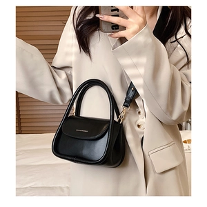 Mirror selfie showing the scale of a black mini crossbody bag with gold hardware