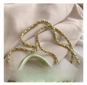 Detail of light green quilted leather bag featuring a gold chain strap and metal hardware