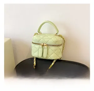 Detail view of mint green quilted mini bucket bag with gold chain strap and dual zippers