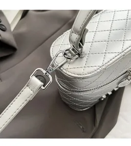 Détail du sac argenté matelassé avec crochets métalliques et bandoulière amovible