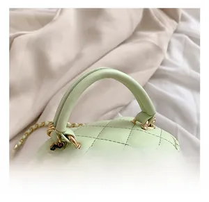 Detail showing mint green quilted mini bag with gold chain and handle on white fabric