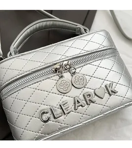 Détail du sac boîte argenté avec double fermeture éclair fluide et breloque en métal