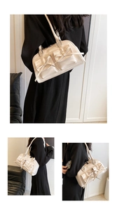 Detail view of cream patent leather tote with bow accents and glossy finish straps