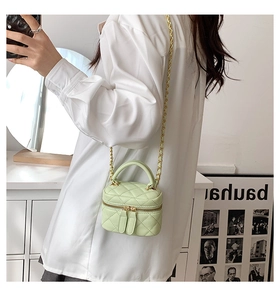 Detail of light green quilted mini bag with gold chain strap on shoulder for women