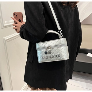 Détail du sac boîte argenté matelassé avec lettres en métal et bandoulière