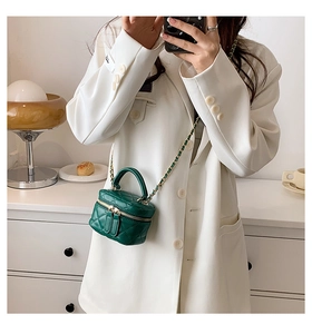 Detail of dark green quilted mini bucket bag with gold chain and leather handle