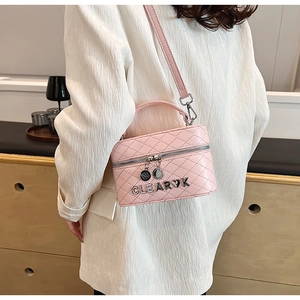 Sac bandoulière rose matelassé avec lettres métalliques porté par un mannequin