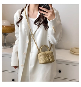 Detail of khaki quilted PU leather mini crossbody bag with gold chain strap on white blazer